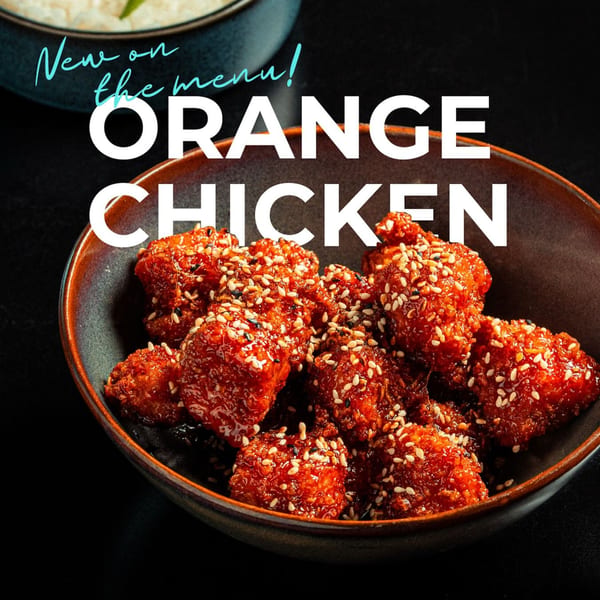 SUSHARK's new orange chicken, coated in sauce and sesame seeds, in a dark bowl.