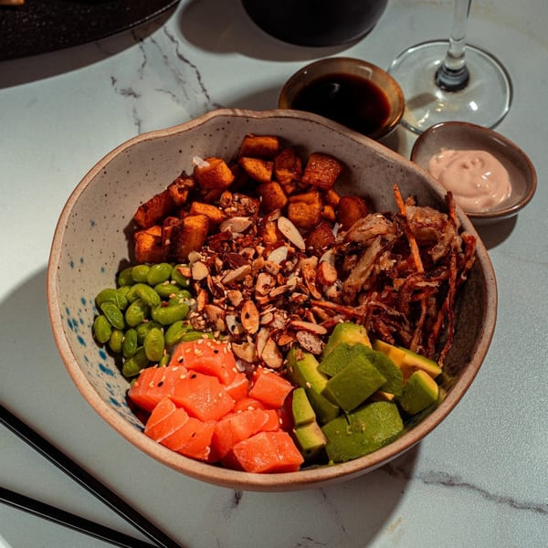 A SUSHARK poke bowl with salmon, avocado, edamame, sweet potato, and crispy onions.